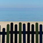 Uno steccato scuro, dietro al quale si vede la sabbia, e poi il mare azzurro. Per noi rappresenta il tono di voce, la personalità