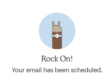 Messaggio di conferma di Mailchimp. Una illustrazione mostra una mano pelosa di scimmia, icona di Mailchimp, con un orologio che fa le corna. Il testo dice: "Rock On! Your email has been scheduled"